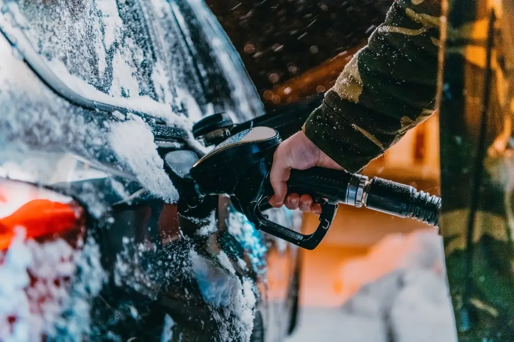 Muž tankuje auto v zime a večer