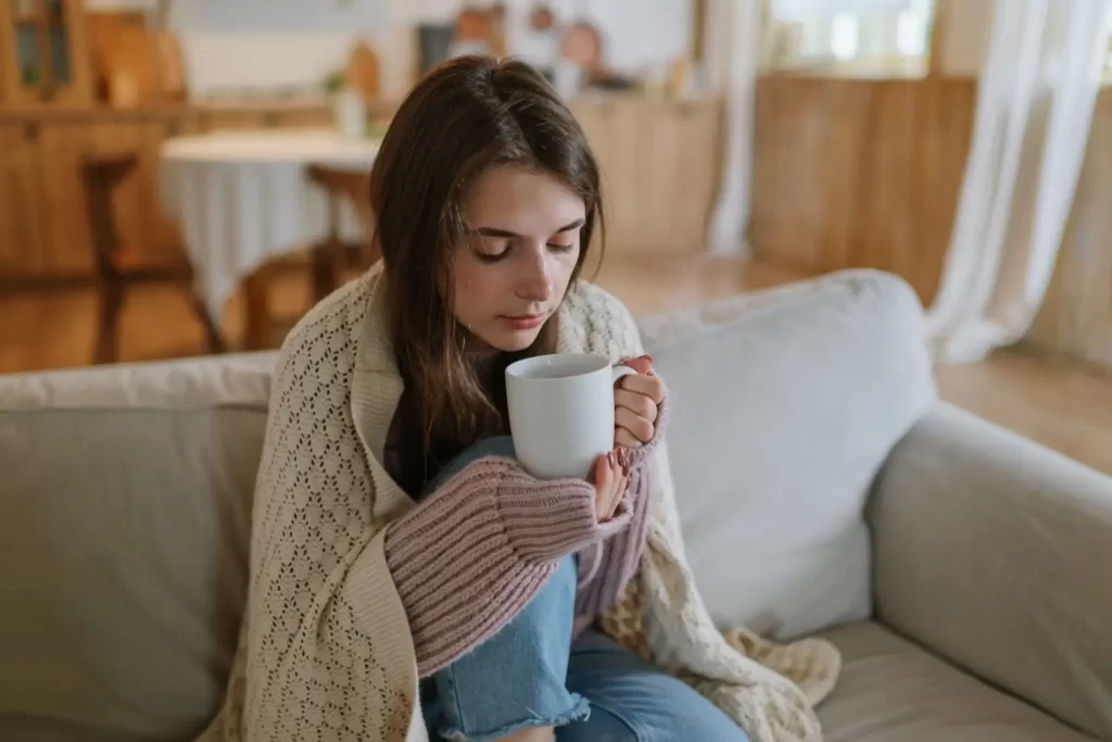 Žena sedí doma s horúcim čajom