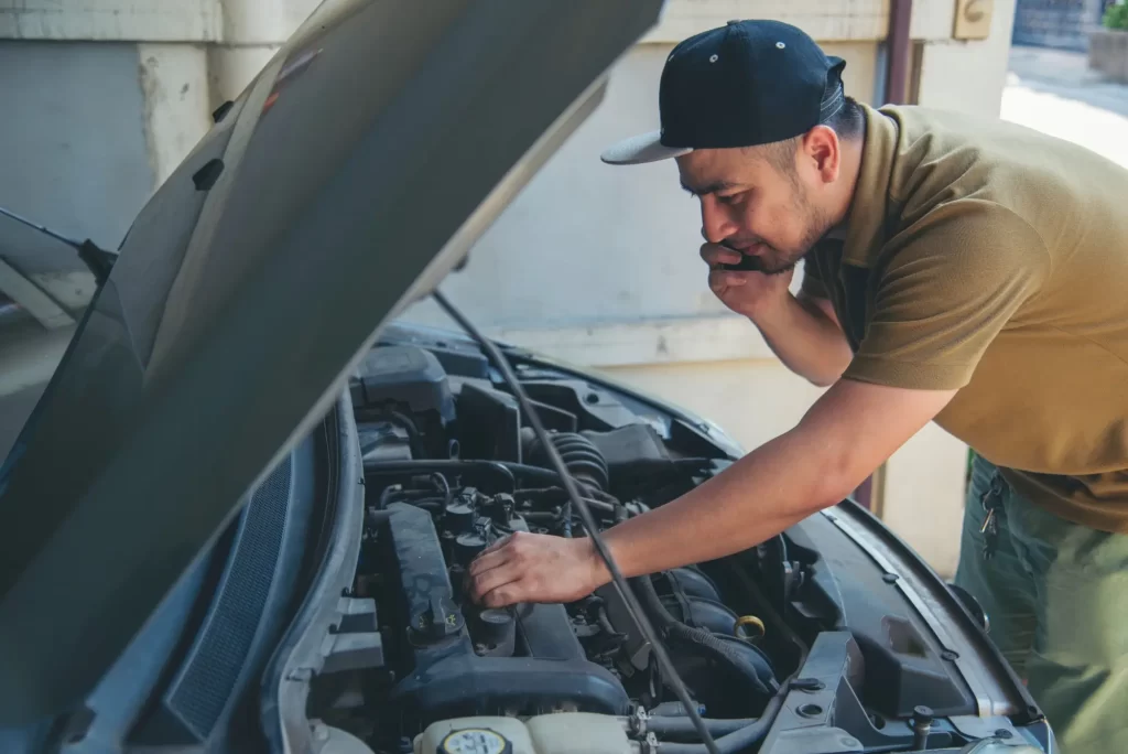 muž opravuje auto