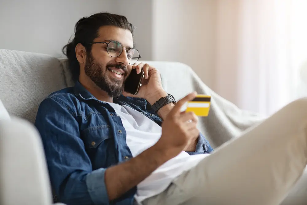 Muž telefonuje a v ruke drží kreditnú kartu