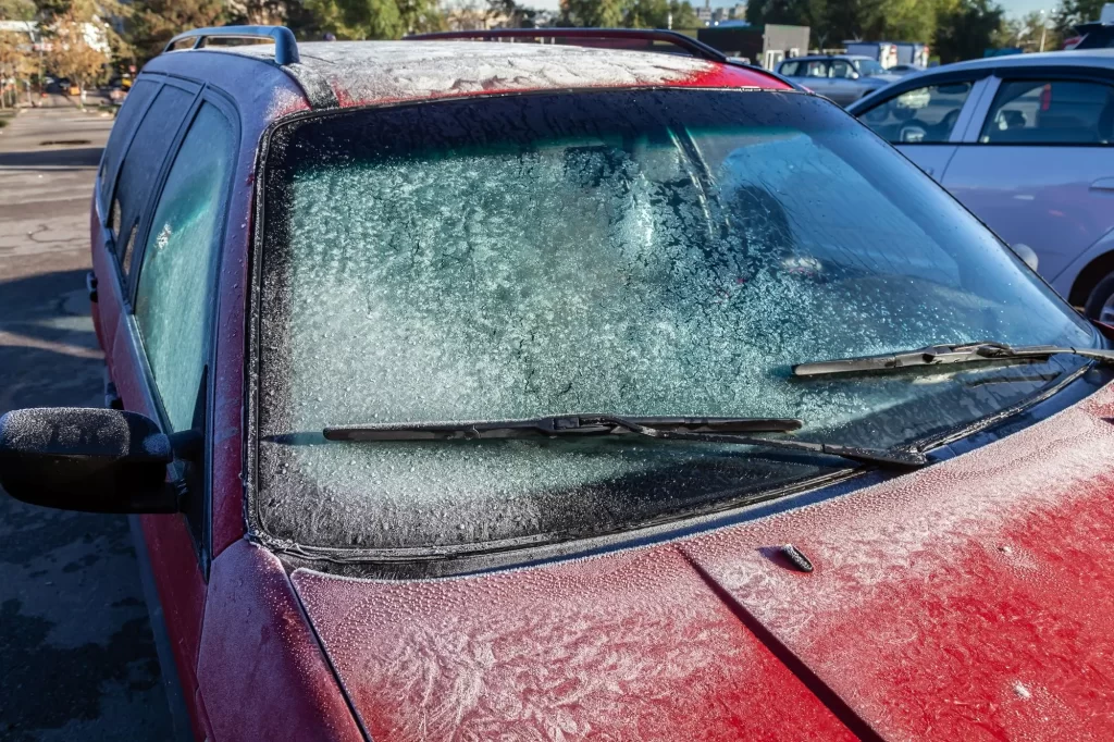 Červené auto so zamrznutým čelným sklom 