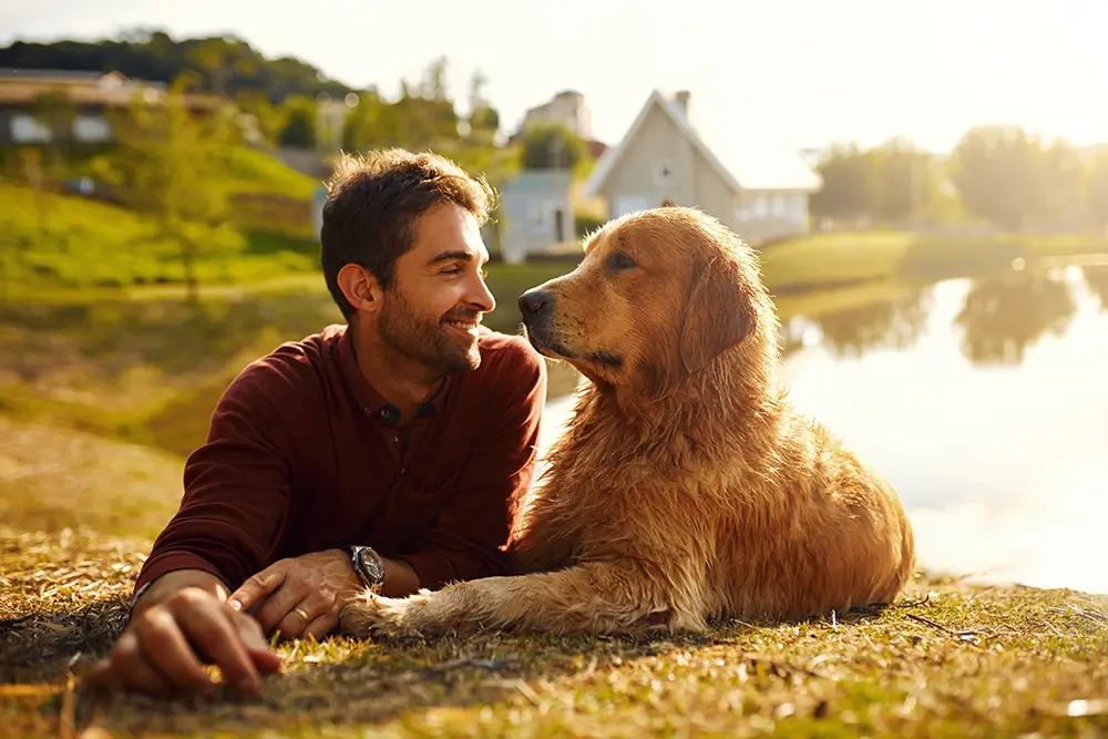 Kozorožci môžu nájsť čas na relaxáciu. - Muž so psom vonku pri rybníku