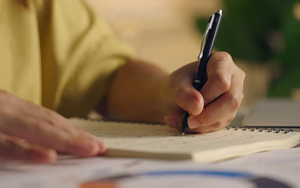 Zapíšte si svoje sny, venujte pozornosť náhodným stretnutiam a malým znamením. - Žena píše do notebooku